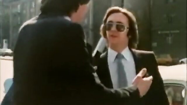 Two suited men in intense 70s gay conversation outdoors