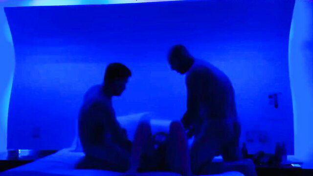 Silhouette gay threesome with men in blue-lit bedroom action