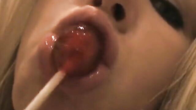 Busty blonde babe seductively sucking red lollipop closeup