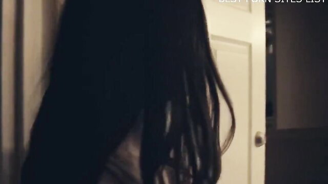 Ava Addams peeking from dark doorway in tense thriller scene