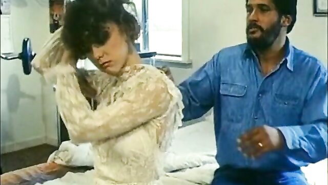 Retro brunette in lace dress gets hair styled by man on bed