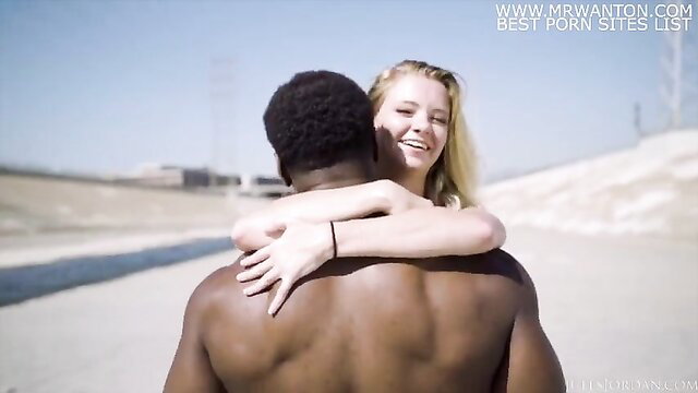 Riley Star hugs muscular black man from behind in sunny outdoor embrace