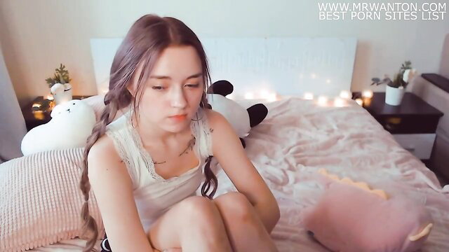 Cute teen with pigtails in tank top sitting on bed looking for daddy