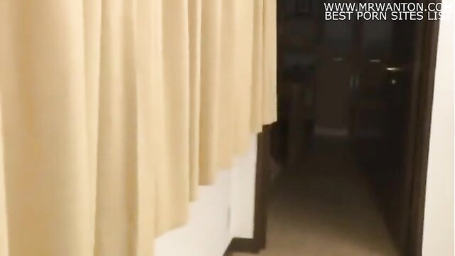 Amateur Asian babe in lingerie peeking through beige curtains in dimly lit room