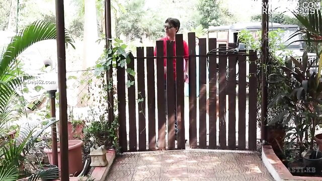 Indian twink in red shirt barefoot at garden gate, teasing pose