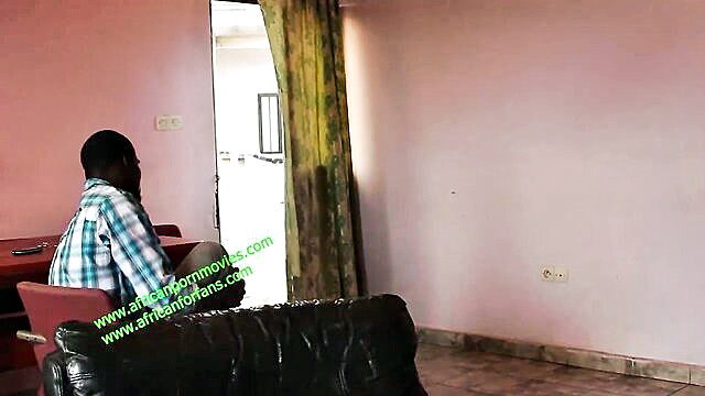 African man in checkered shirt sits in pink room, African Porn Movies watermark