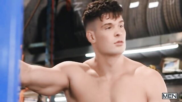 Muscular Malik Delgaty punches heavy bag shirtless in gym