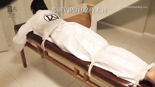 Bound Chinese woman in white dobok tied prone on bench for hand spanking BDSM