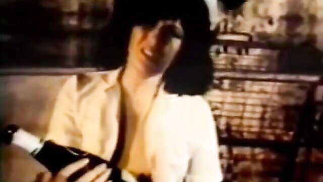 Vintage BDSM woman in sheer blouse holds champagne bottle seductively