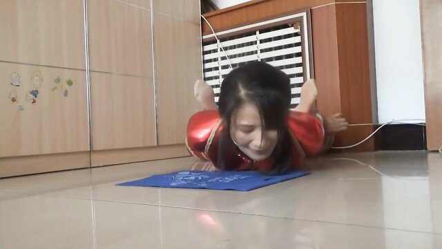 Chinese woman in red bodysuit hogtied on floor in BDSM scene