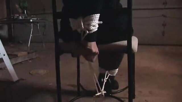 Woman bound to chair with ropes in intense BDSM bondage scene