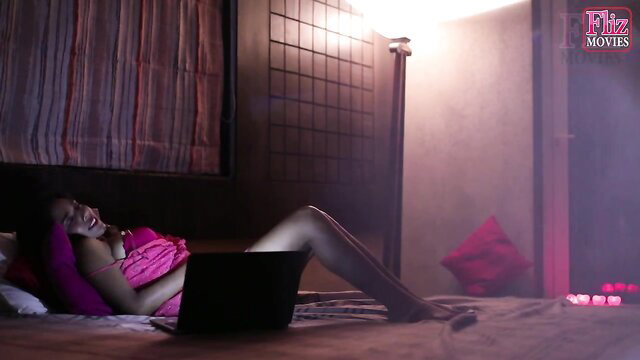 Indian babe in pink lingerie lounging seductively on bed in erotic scene