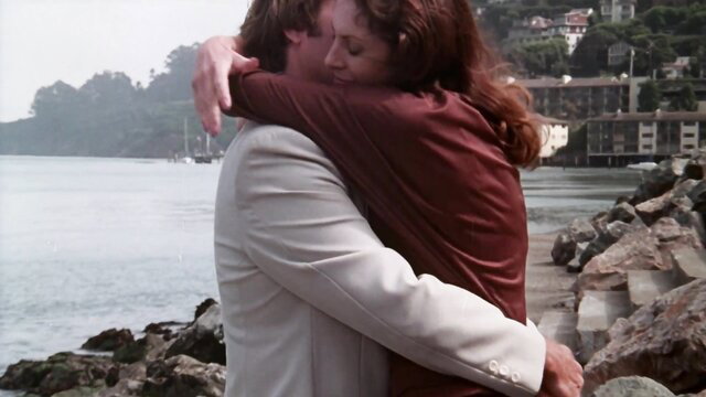 Kay Parker in romantic embrace by the water in classic porn