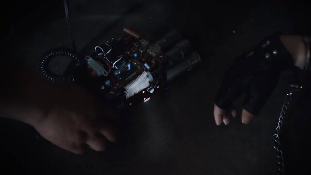 Dark closeup of bomb device on gloved hands in shadowy fetish scene