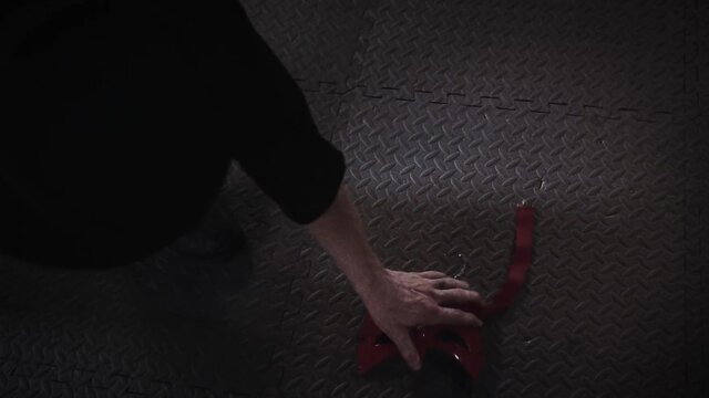 Closeup of woman's hand gripping red bondage strap on gym mat