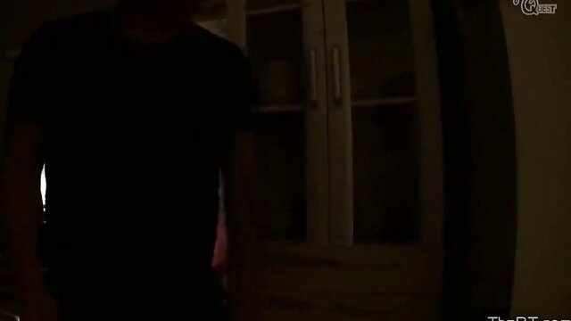 Mystery man in dark shirt at cabinet in dim bedroom scene