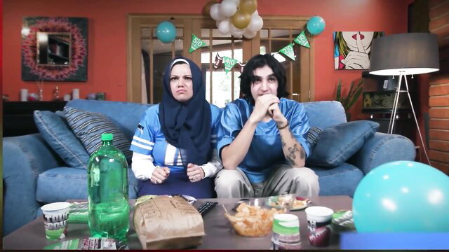 Arab mommy in hijab and son in jerseys on game night couch