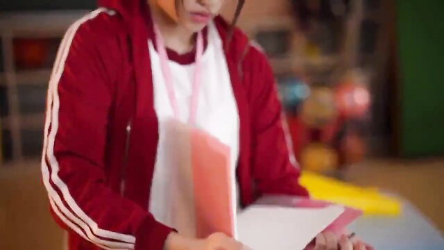 Cute Japanese girl in red tracksuit reading papers in classroom threesome preview