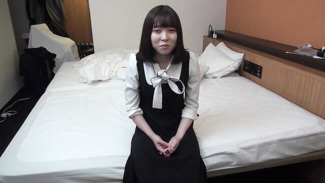 Cute Japanese schoolgirl in sailor uniform sitting on bed, innocent look