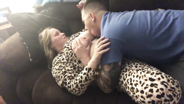 Woman in leopard print pajamas and man embracing on a couch