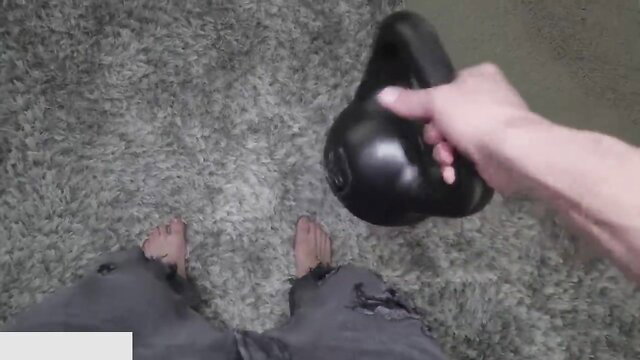 Christy Love's bare feet and hand holding black kettlebell in torn jeans