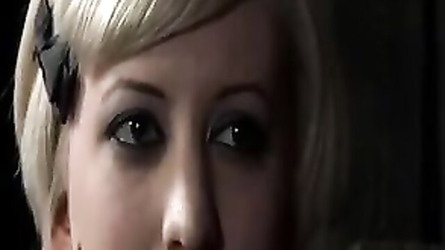 Sister Dee closeup with blonde bob, black bow, intense eyes