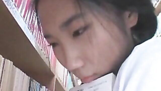 Asian JAV girl in white blouse reading book closeup in library