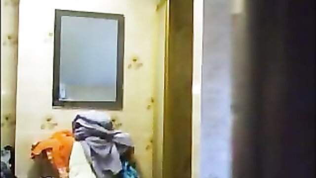 Granny spied in bathroom: orange top, purple towel over lap, mature nude