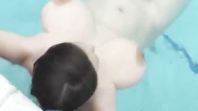 Topless Asian woman with big tits floating nude in pool