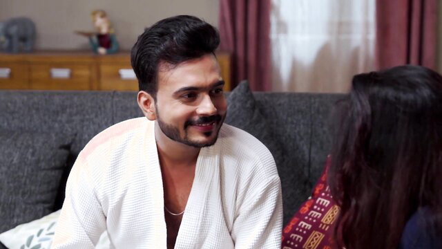 Desi busty bhabhi in robe smiles at man on couch in casting scene