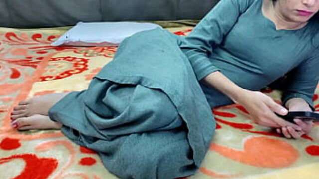 Punjabi girl in teal salwar kameez lounging on bed holding phone