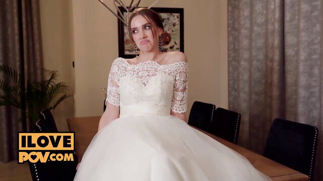 Runaway bride in lace wedding dress sits poised at table, POV tease