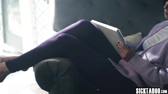 Kira Noir in purple leggings reading on couch, sexy legs up