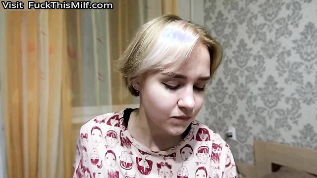 Blonde amateur teen in printed top looks down shyly in closeup