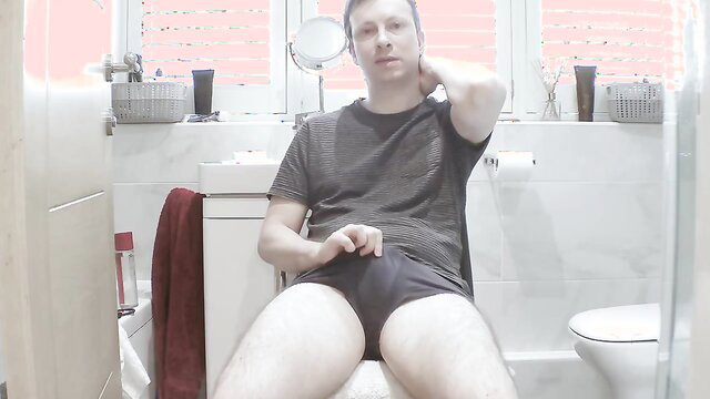 Nude white guy in gray tee and underwear masturbating on toilet in bathroom