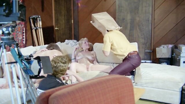 Retro orgy scene with nude blonde on couch, paper bag heads