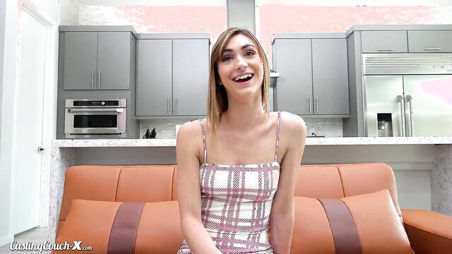 Ana Rose in a plaid dress sitting on a couch