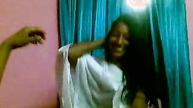 Indian college girl in white dress smiling with hand on neck in bedroom
