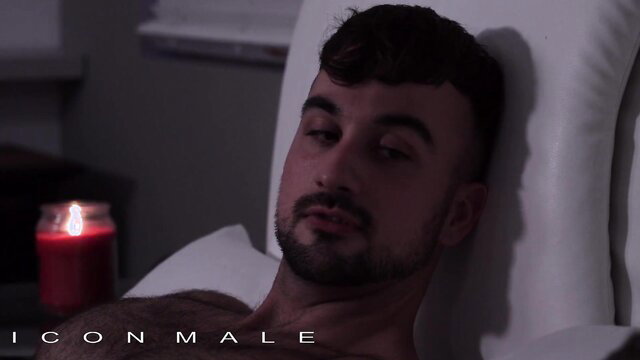 Handsome shirtless man reclining on bed by candlelight