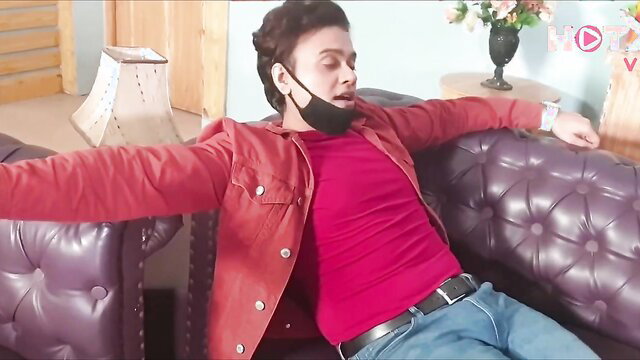Riya Bhabhi relaxes in red jacket on couch, busty Indian MILF BTS