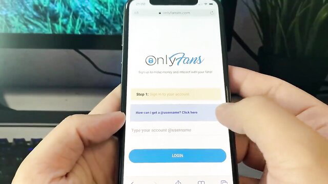 OnlyFans login screen on iPhone held by hand
