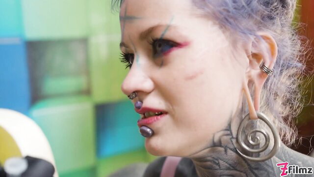 Alt woman with purple hair, face tattoos, piercings closeup