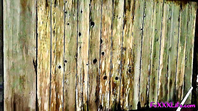 Woman showering nude outdoors on weathered green wood fence in woods