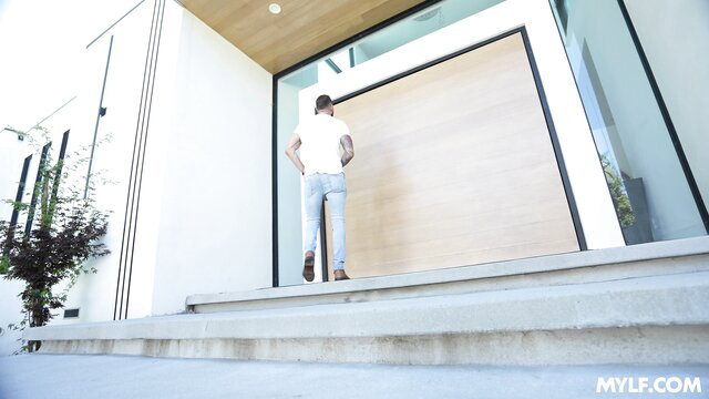 Quinton James approaches modern home entrance in tight tee and jeans