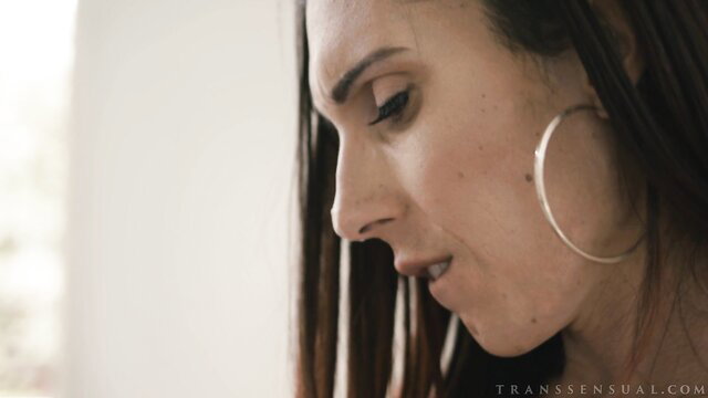 TS Foxxy closeup profile with big hoop earrings, sultry gaze