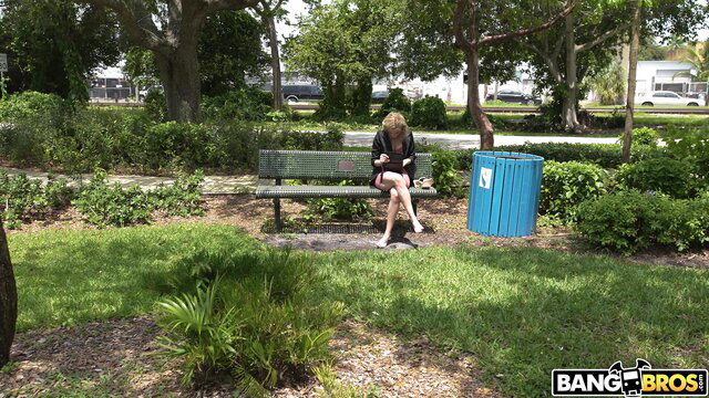 Lindsey Lakes sits legs spread on park bench in Bang Bus