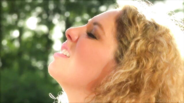 Blonde curvy Jessy Dubai smiles in sunny outdoor closeup