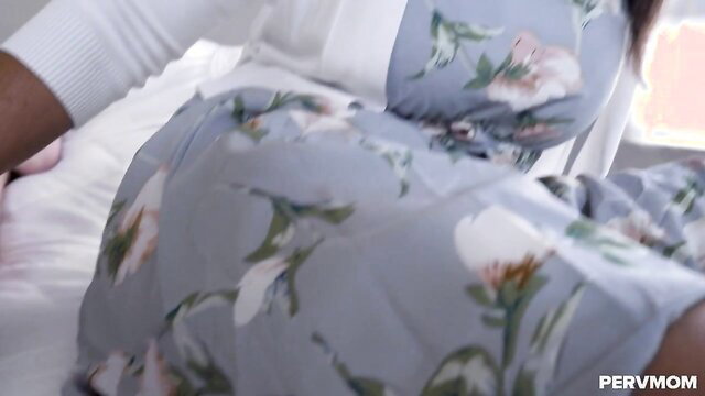 Hot black stepmom in floral dress bends over bed in doggy pose