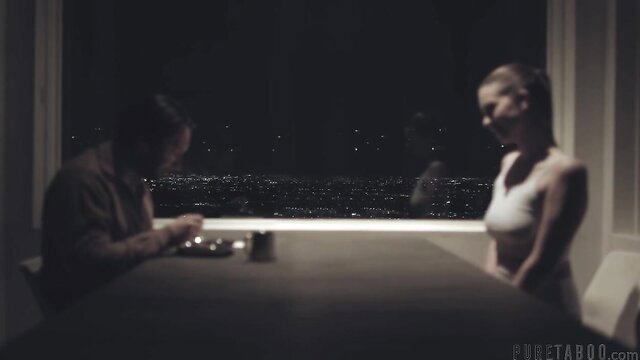 Jill Kassidy in white tank top with Tommy Pistol at table, city view