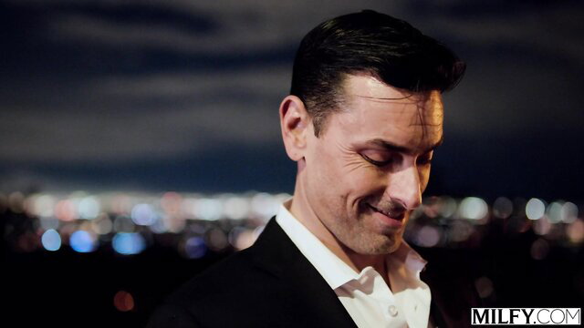 Phoenix Marie smiling seductively in suit overlooking city lights